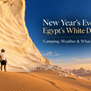 Traveler standing beside a massive white limestone formation in Egypt’s White Desert at sunset, with New Year’s Eve 2027 travel guide title overlay.