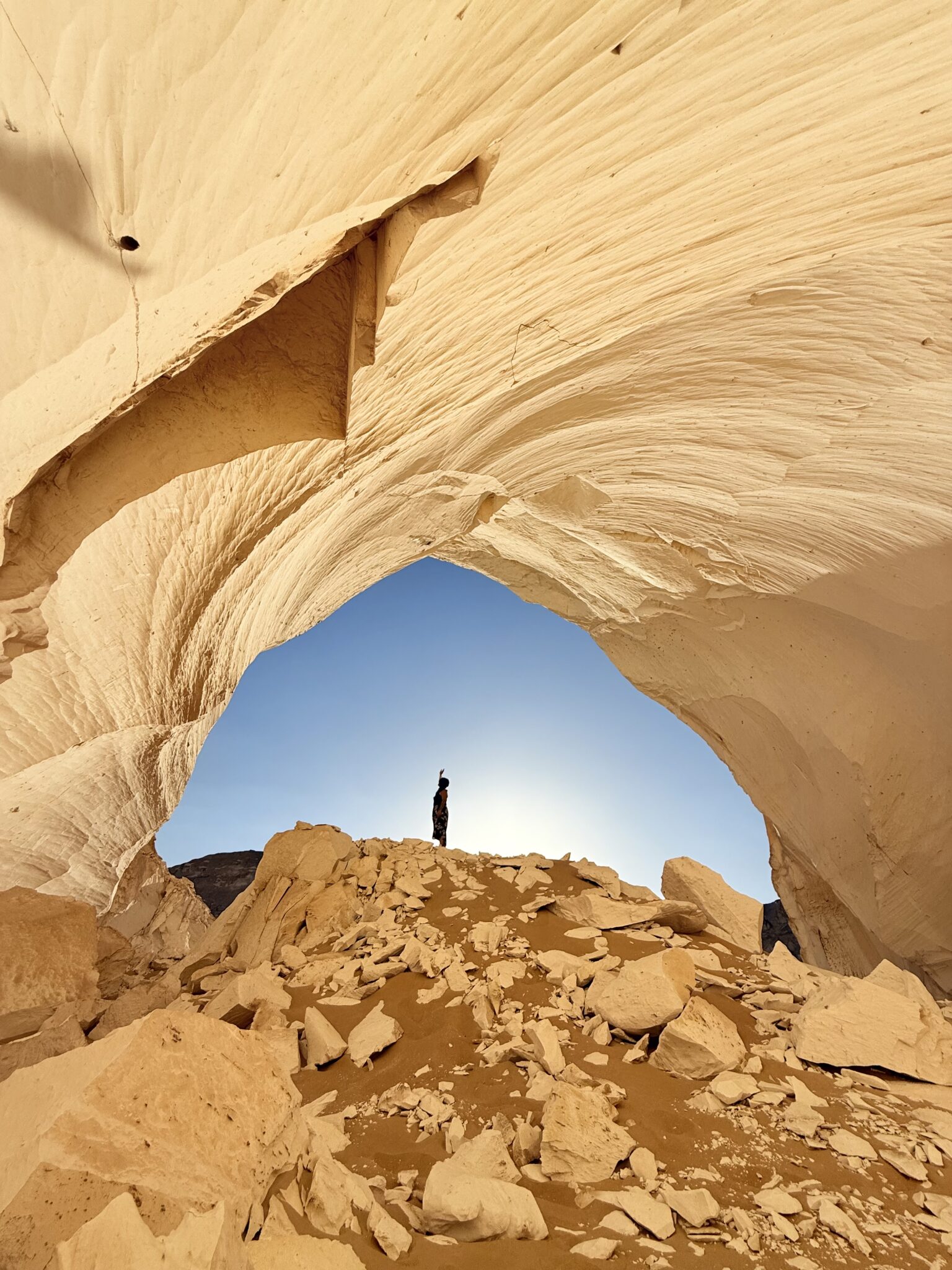 Traveler standing beneath a natural rock arch in Egypt's White Desert